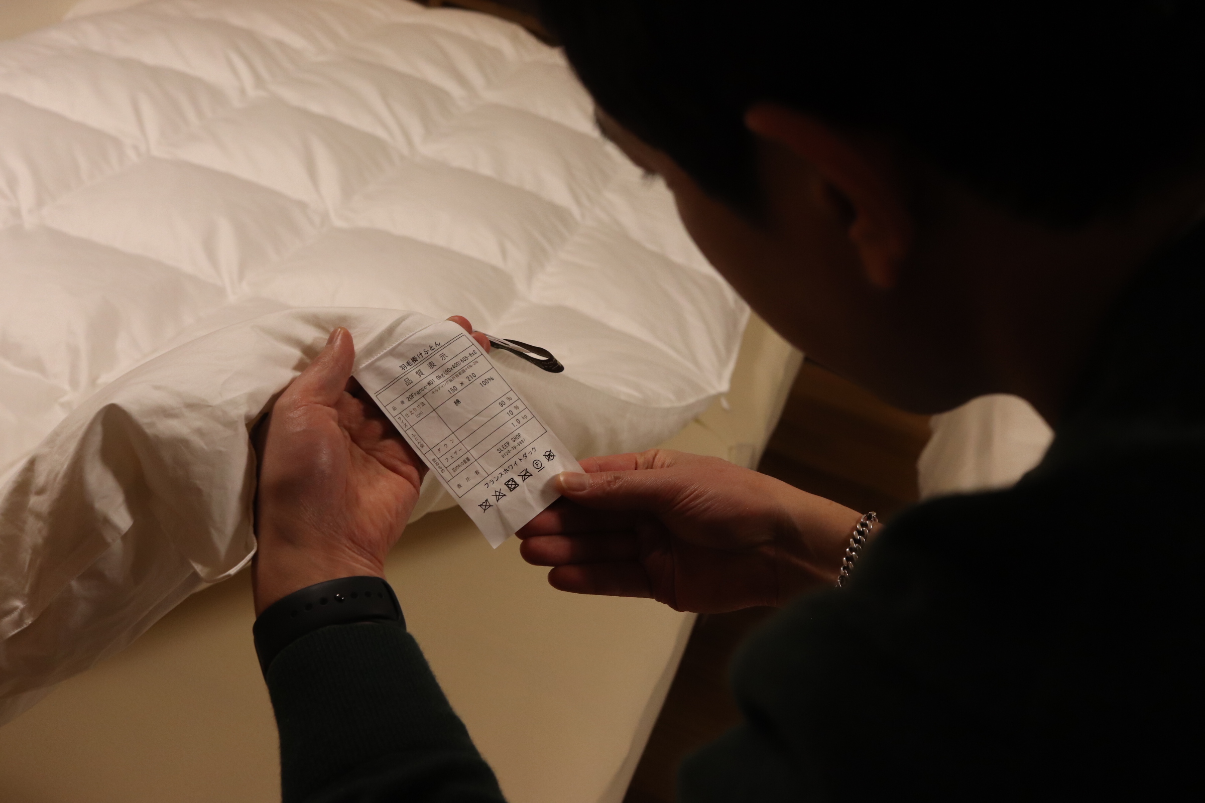 布団の商品タグをチェックする写真